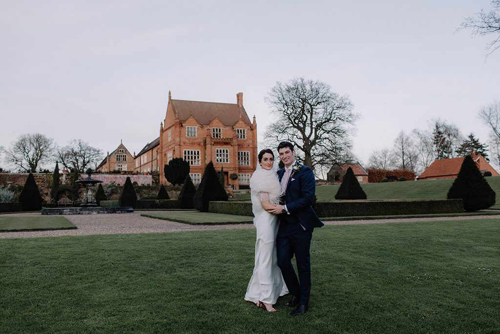 The bride and groom pose in front of the stunning Oxnead Hall wedding venue in Norfolk
