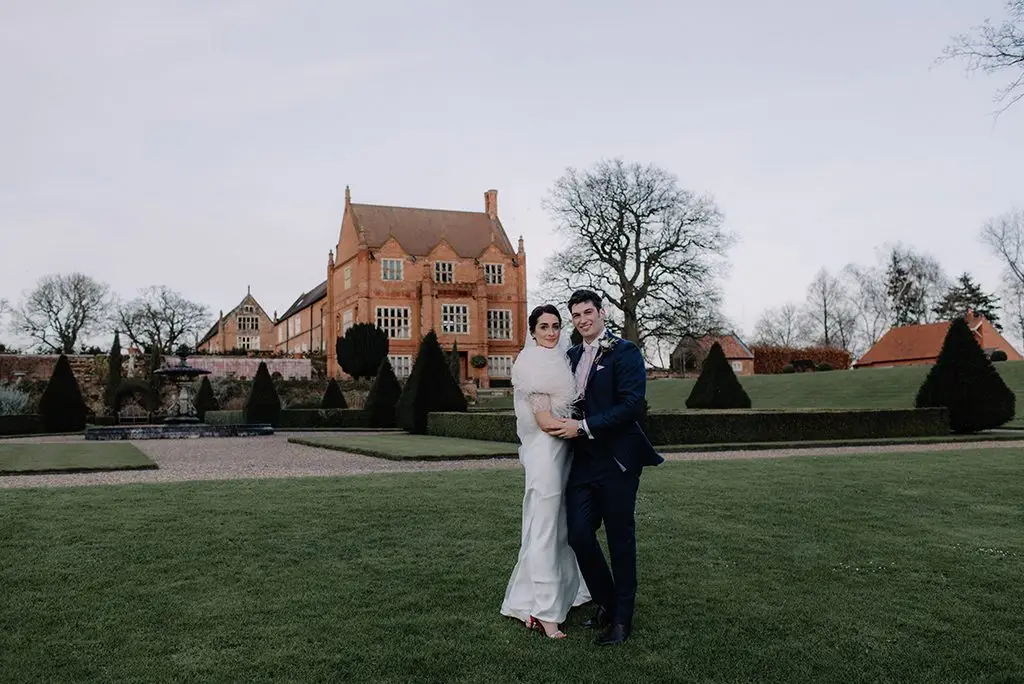 The bride and groom pose in front of the stunning Oxnead Hall wedding venue in Norfolk